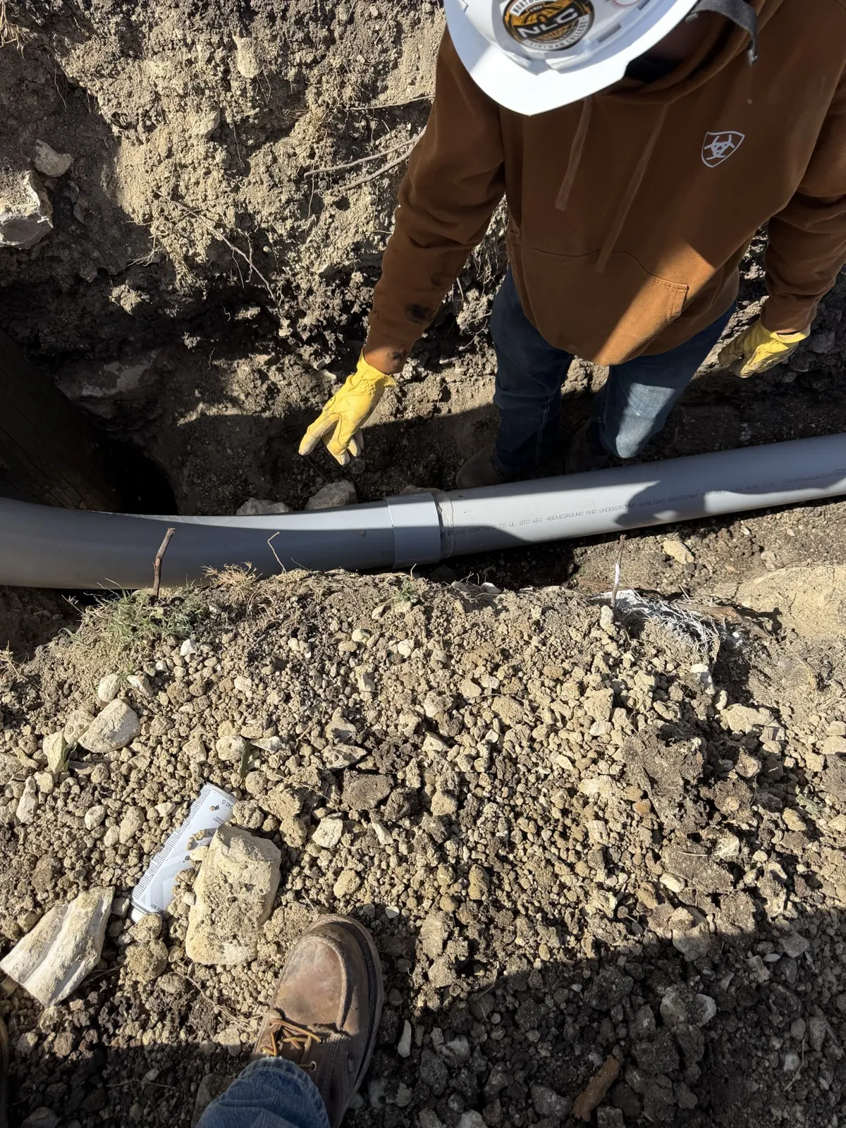 Crew placing underground conduit in a trench at a Tesla charging station site in Saginaw, TX
