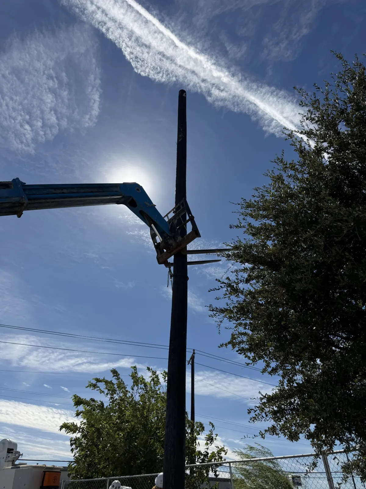 Telehandler supporting a utility pole during setting at a Tesla charging station site in Saginaw, TX